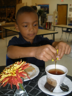 Elementary student preparing tea with honey.